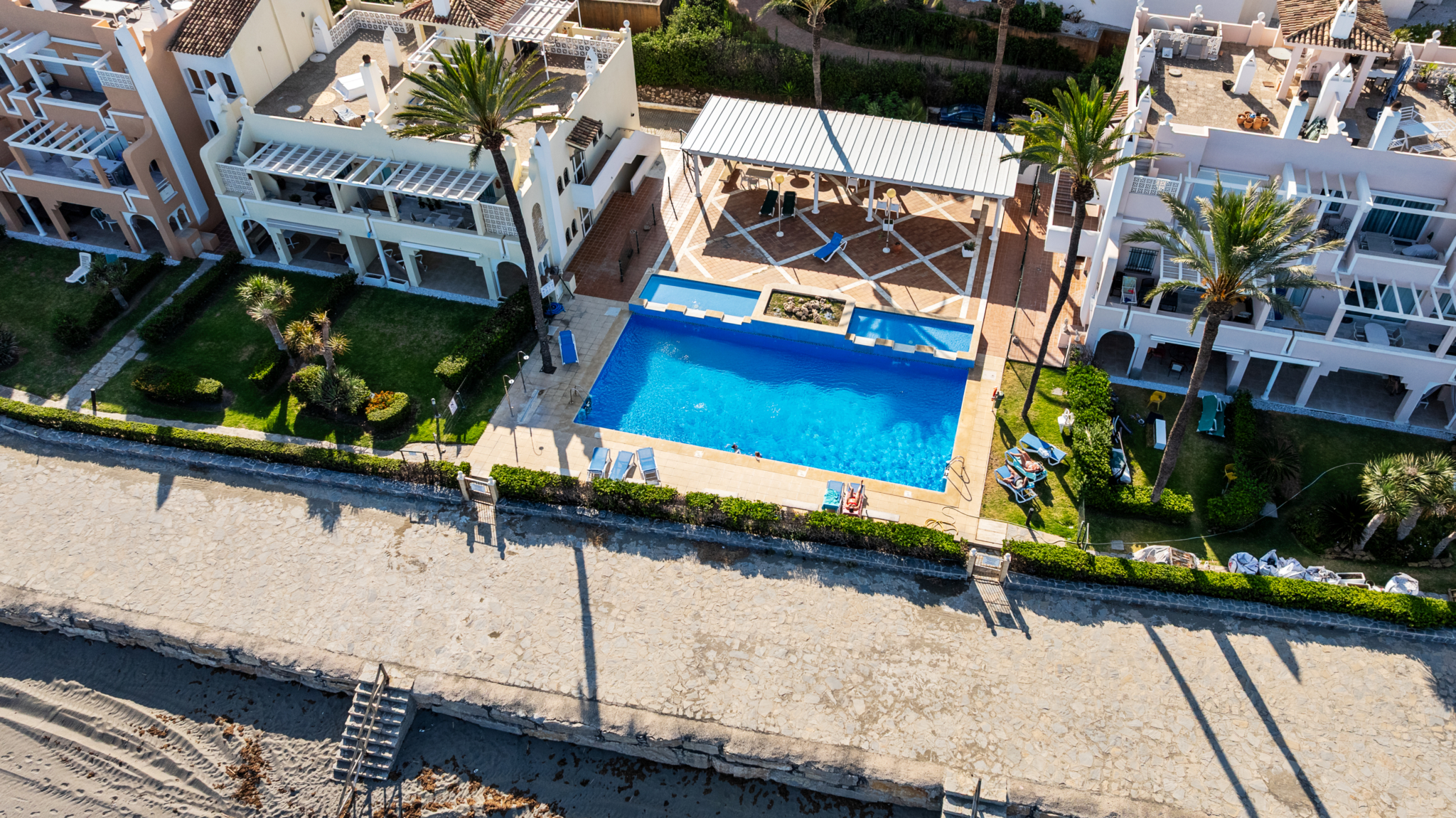 Aerial view of Playa del Moral beachfront apartments with communal pool and gardens overlooking the Mediterranean Sea