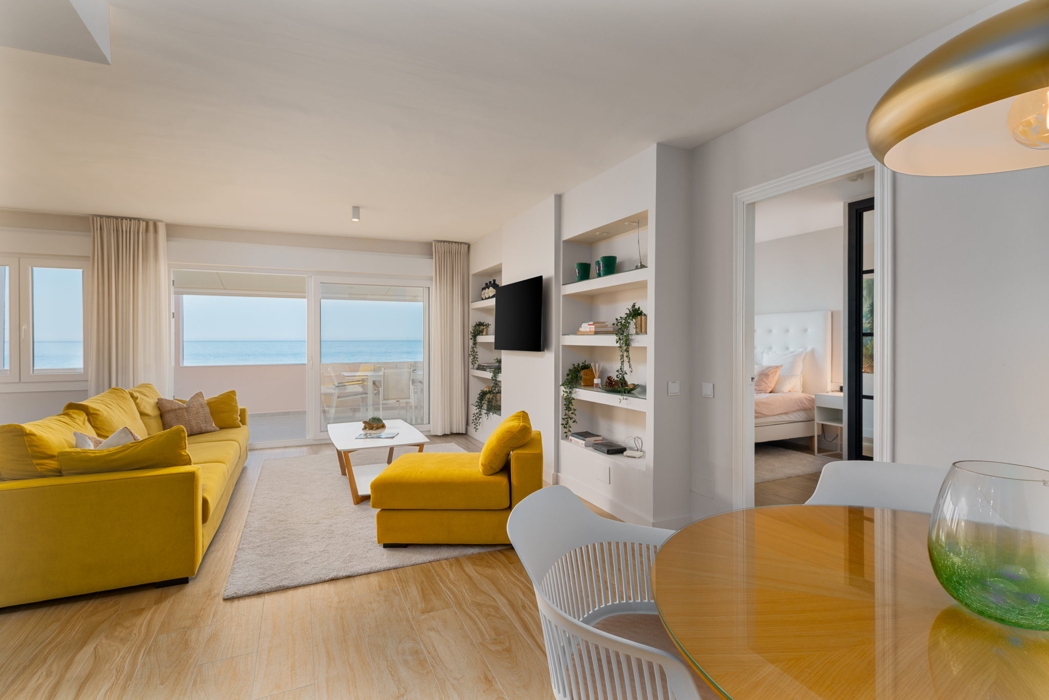 Modern beachfront living room with sea views, yellow sofas, and dining area in Playa del Moral apartment