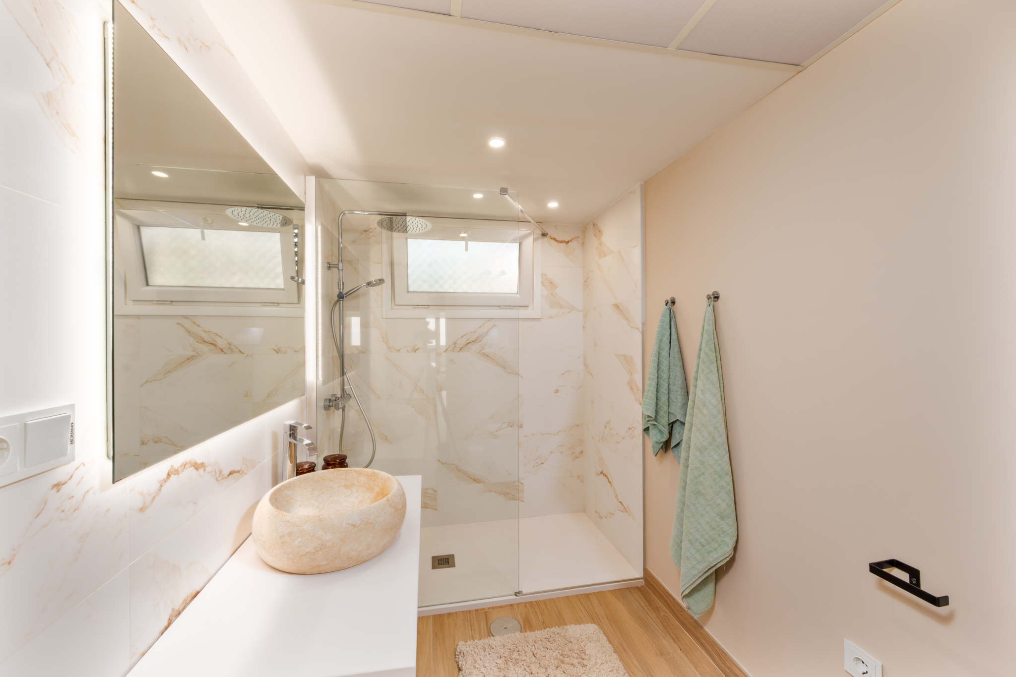 Modern bathroom with marble shower and stone sink in Playa del Moral beachfront apartment.