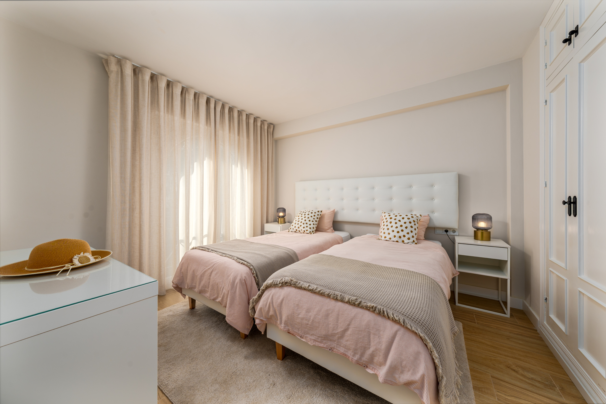 Bright twin bedroom with large windows and balcony at Playa del Moral apartment.