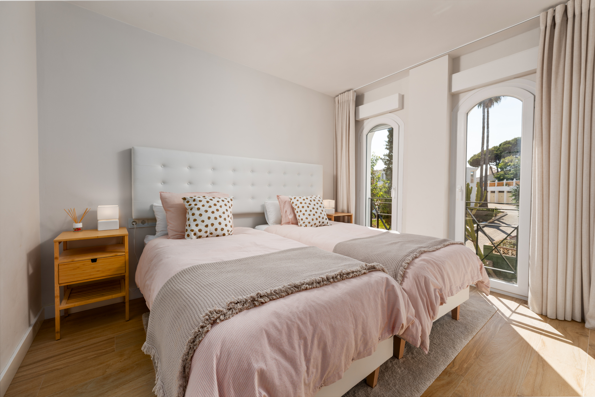 Bright twin bedroom with large windows and balcony at Playa del Moral apartment.