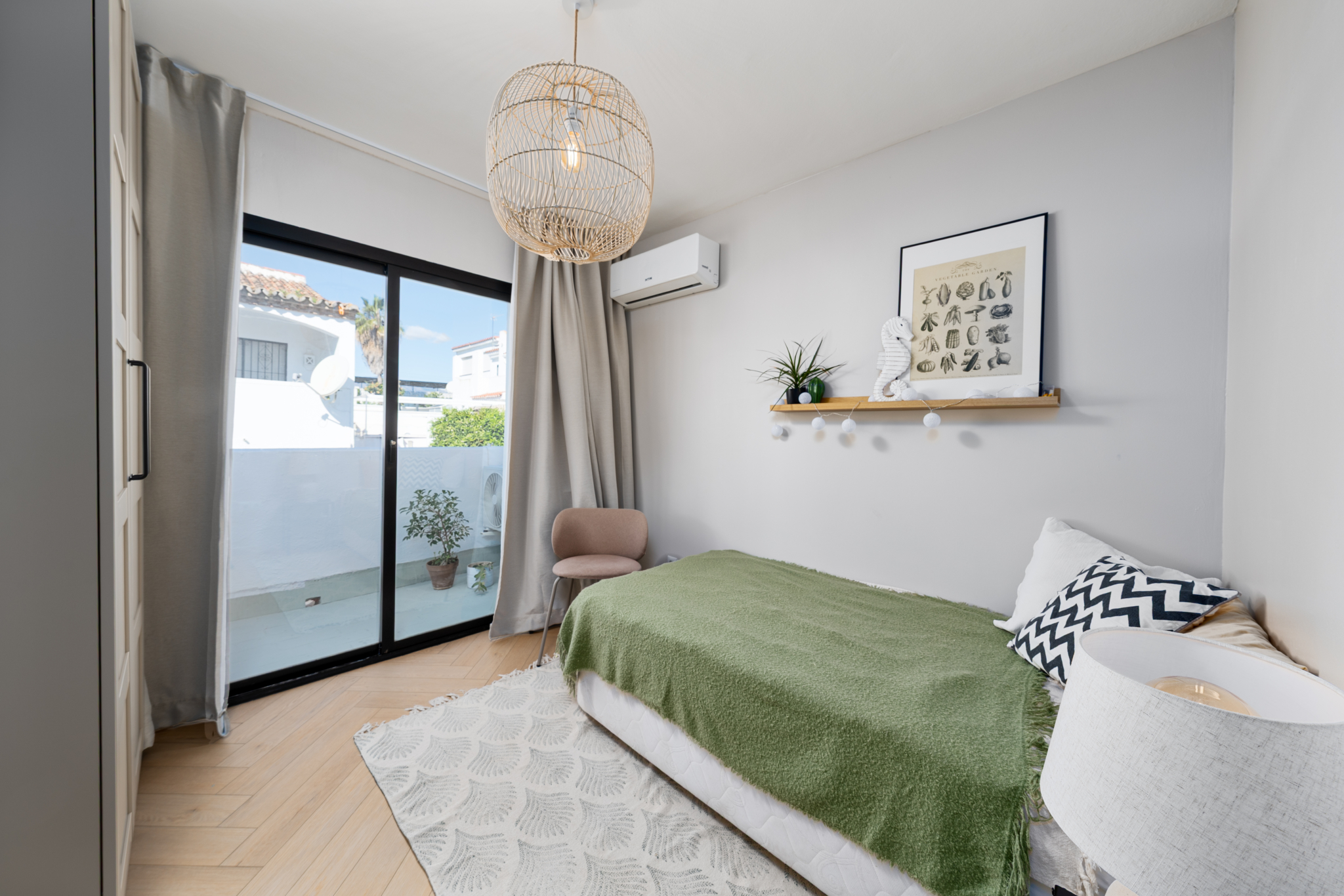 Bright guest bedroom in Bel-Air semi-detached house near Marbella, featuring minimalist decor, sliding glass doors, and neutral tones with green accents.