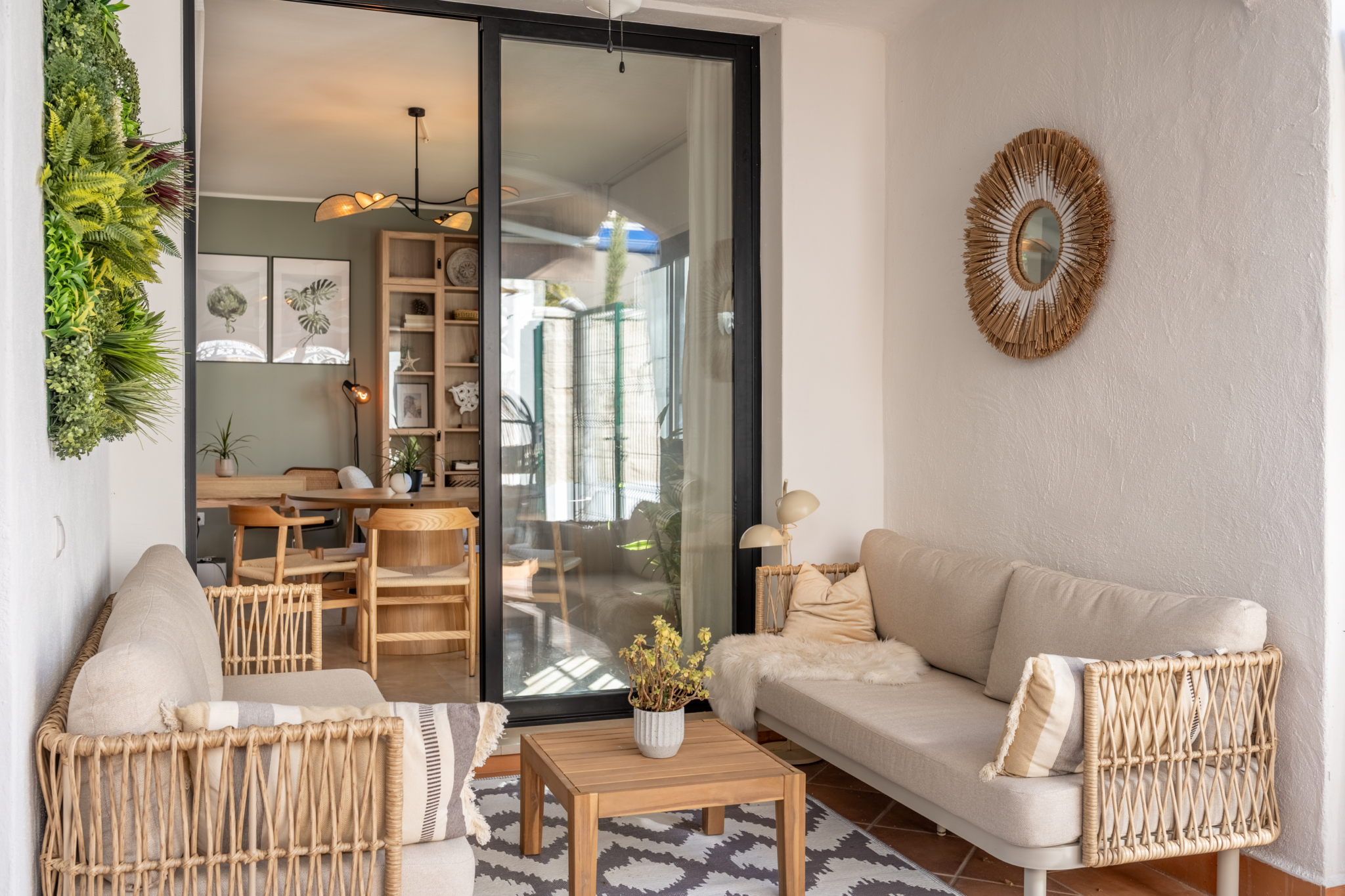 Cozy terrace lounge in Bel-Air semi-detached home near Marbella, with natural rattan furniture, indoor plants, and view into the modern dining area