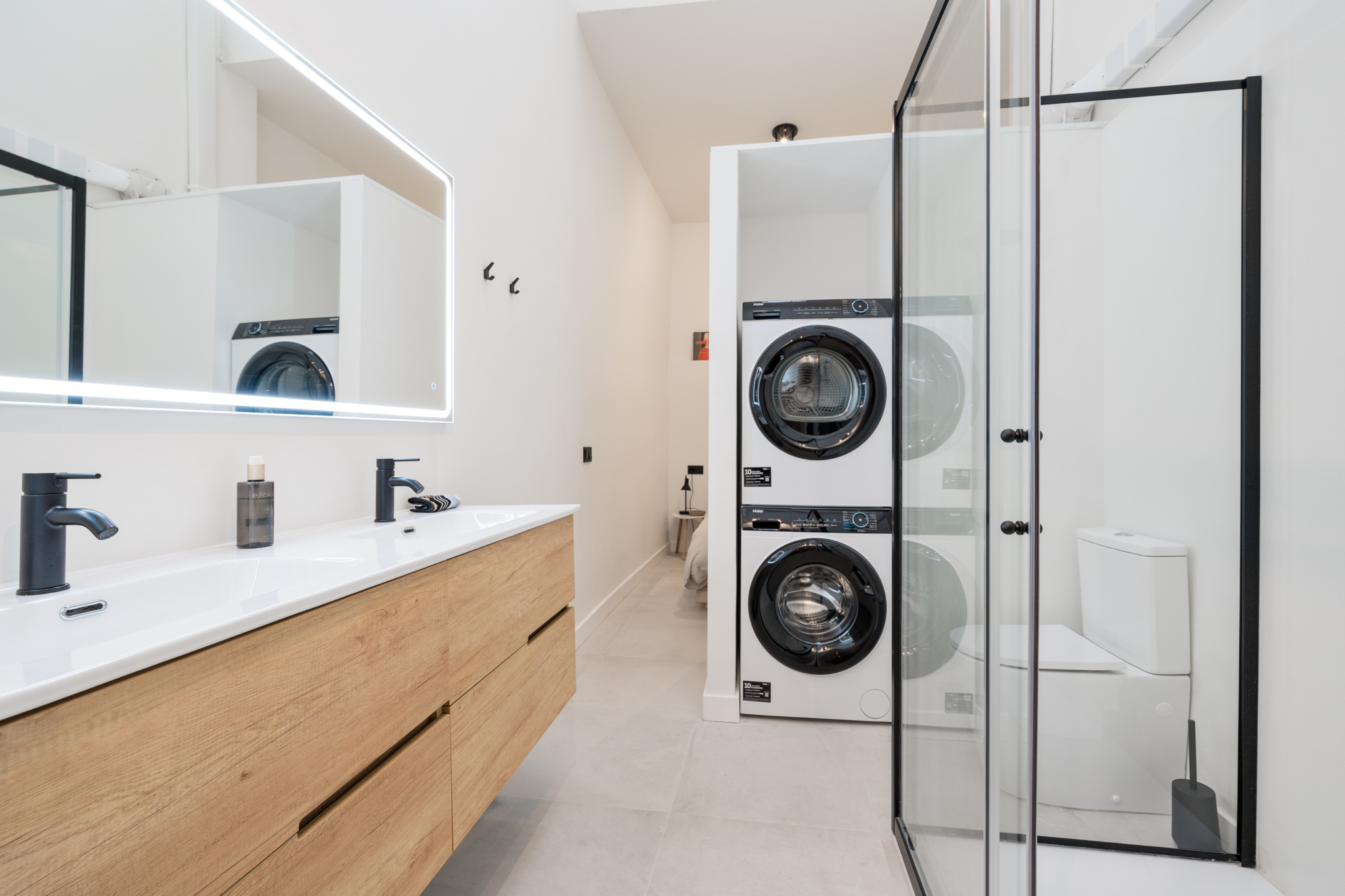 Modern bathroom with wood vanity, glass shower, and laundry area in Estepona old town apartment