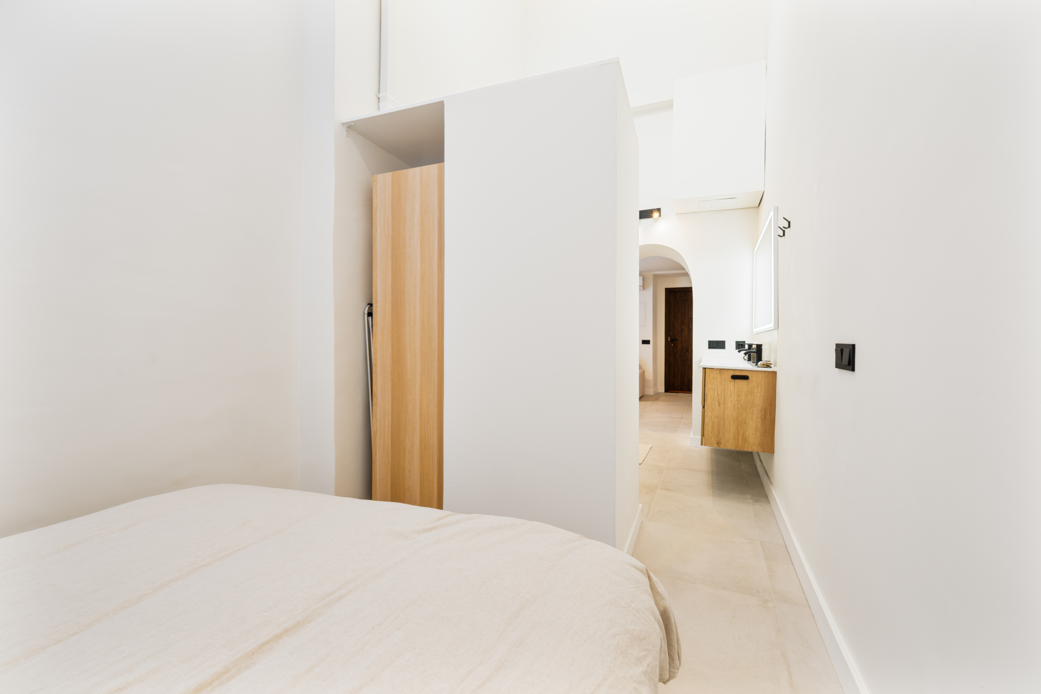 Bright minimalist bedroom with neutral decor and ensuite bathroom in Estepona old town apartment