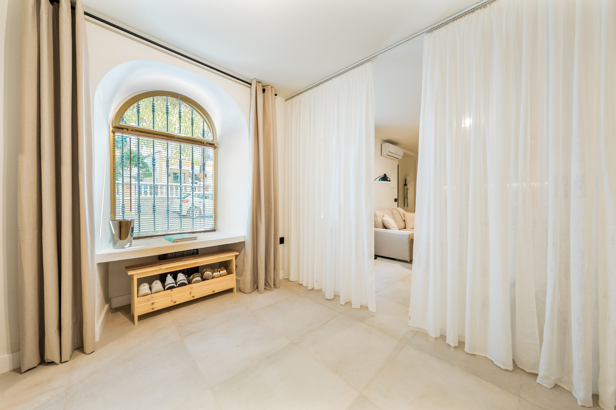 Bright interior with arched window, light curtains, and modern neutral decor in Estepona old town apartment