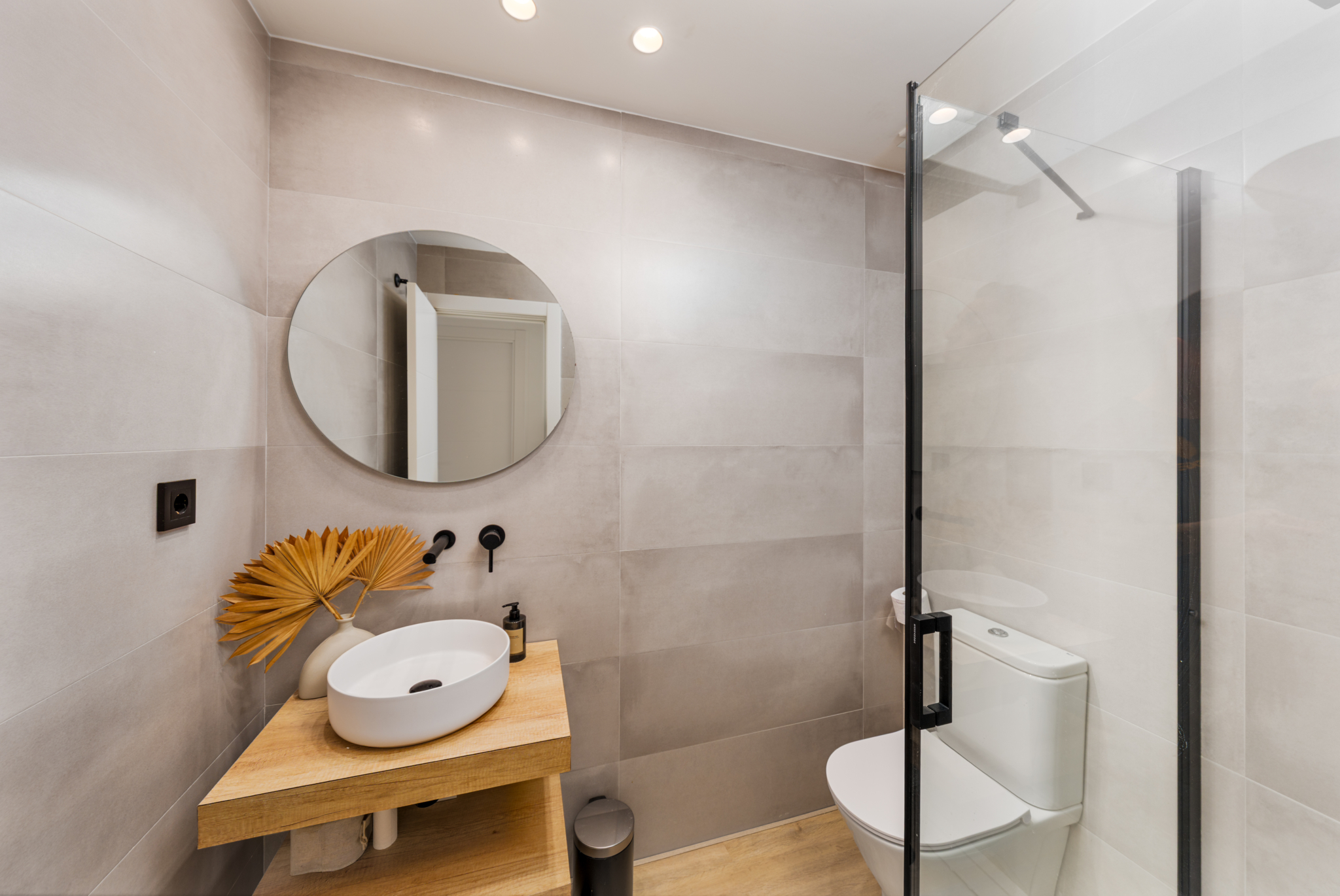 Modern guest bathroom with walk-in shower and round mirror at Los Pinos de Aloha, Marbella