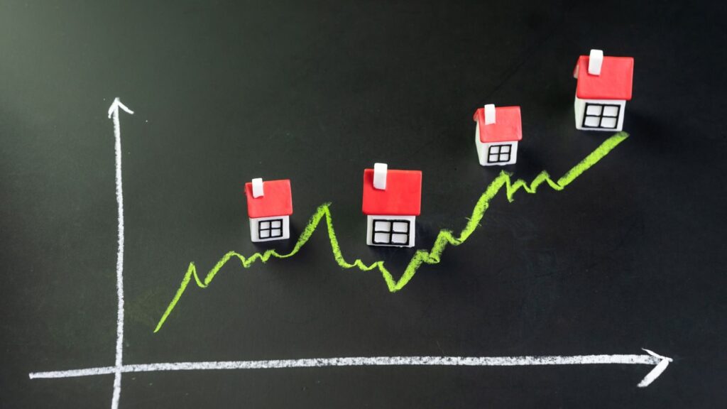 Rising property prices in Nueva Andalucía shown with miniature houses on an upward graph, illustrating growth in the real estate market and highlighting the average property prices in Nueva Andalucia.