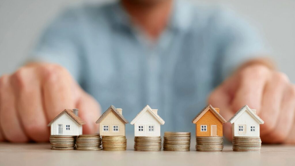 Miniature houses on stacked coins representing rental yields and property investment returns in Nueva Andalucía, showcasing strong Nueva Andalucia rental yields in Marbella.
