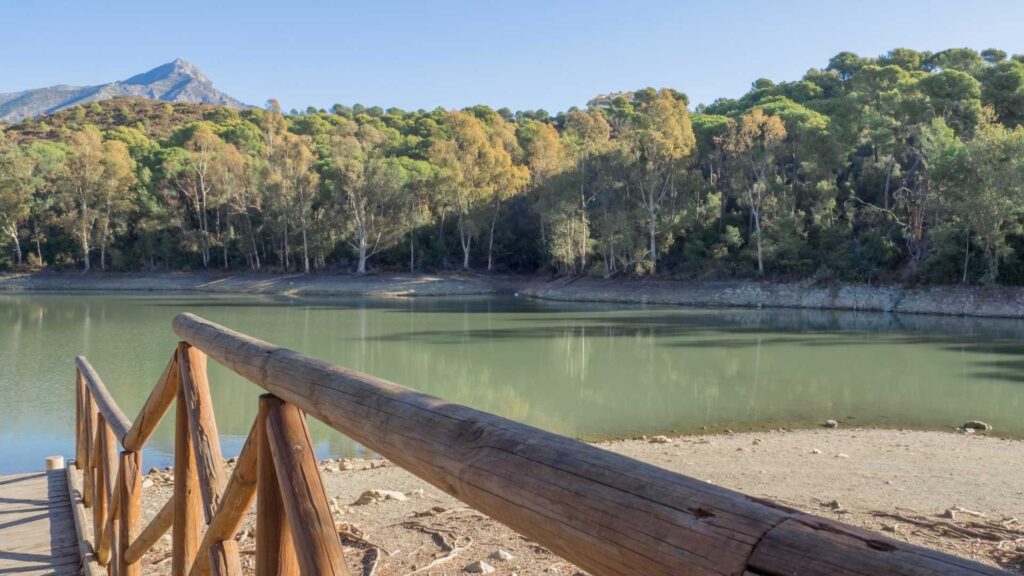 Scenic view of lake and mountains near Nueva Andalucía, Marbella, surrounded by pine forests — a popular area for luxury villas and highly sought-after villas for sale in Nueva Andalucia.