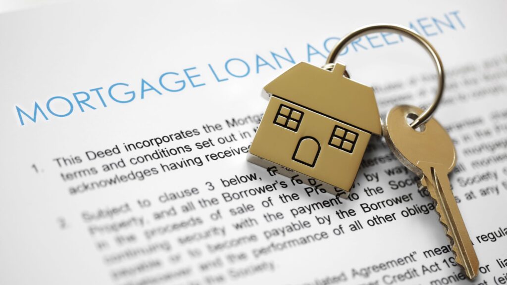 House-shaped keychain and key placed on a mortgage loan agreement document.