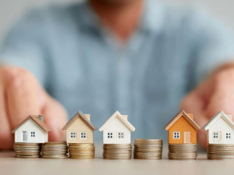 Miniature houses on stacked coins representing rental yields and property investment returns in Nueva Andalucía, showcasing strong Nueva Andalucia rental yields in Marbella.